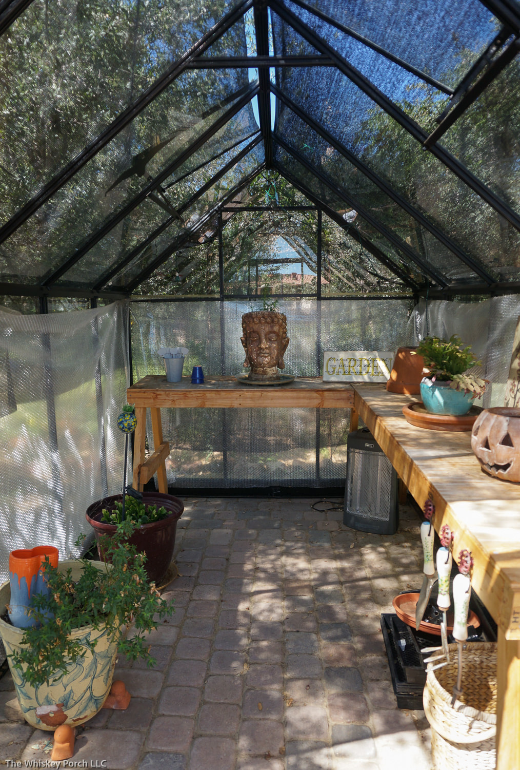 A large buddah sculpture sits at the end of a small greenhouse