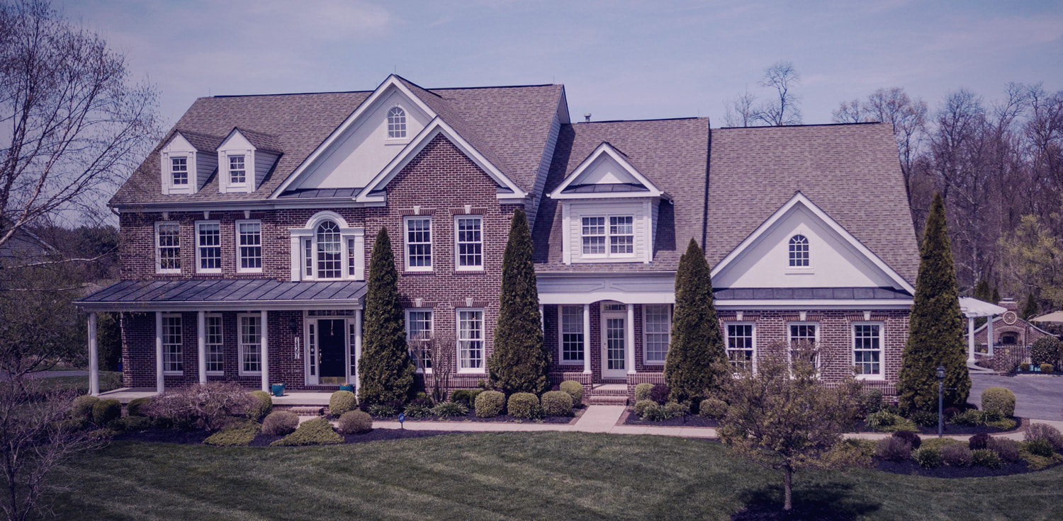 large, brick suburban home with manicured lawn