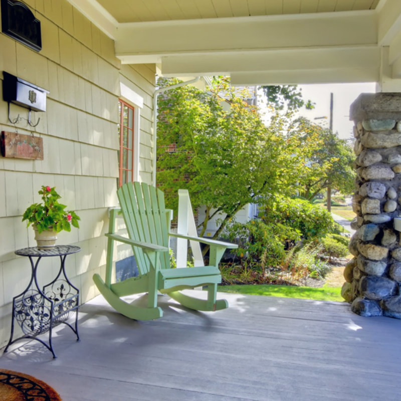 an inviting covered porch with an adirondack rocking chair